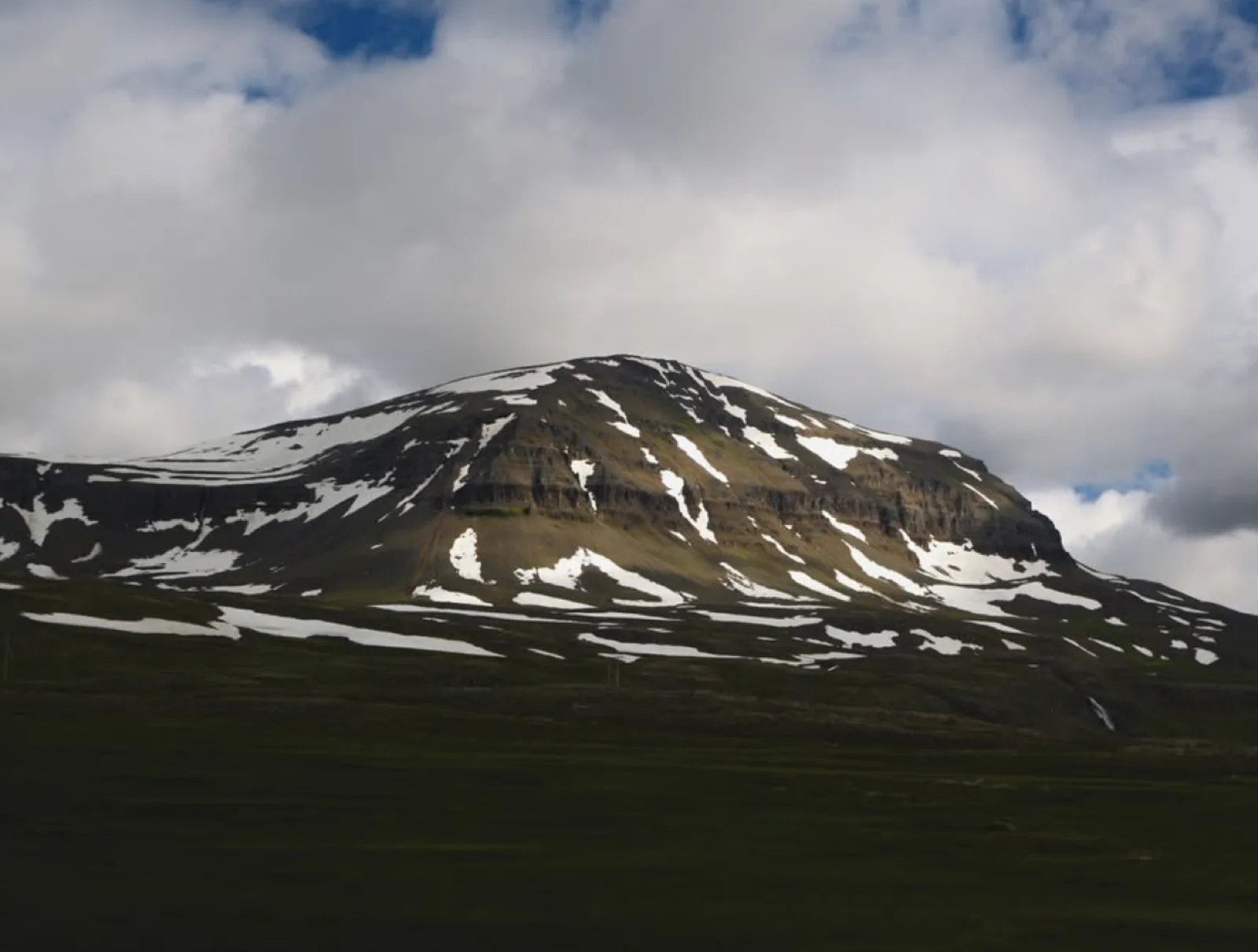 A snow-streaked mountain under cloud