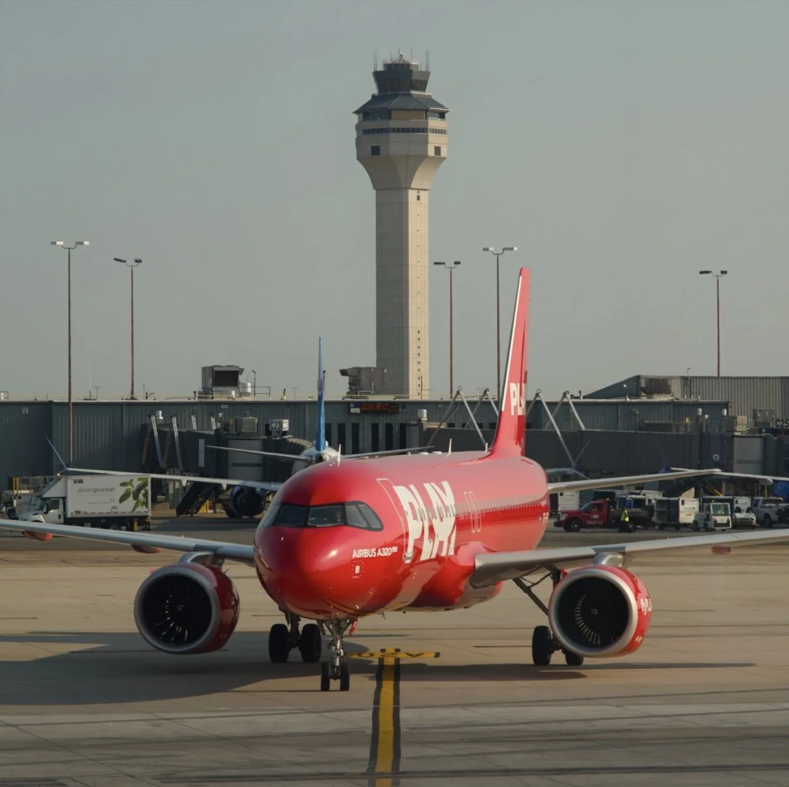 A red airliner at the gate beneath the tower